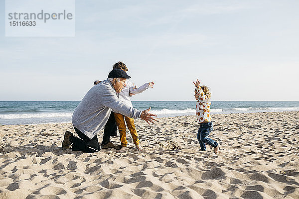 Großvater spielt mit seinen Enkelkindern im Frühling am Strand