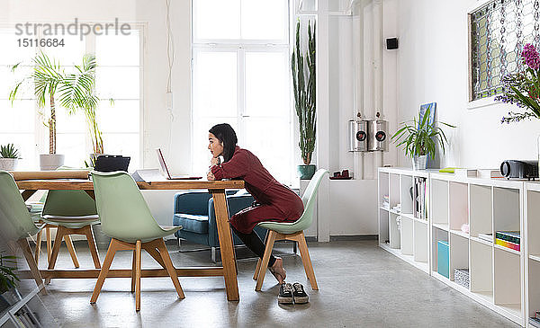 Frau mit Laptop am Tisch im modernen Büro