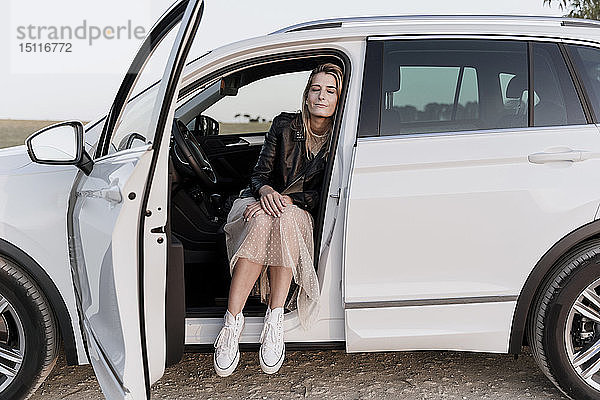 Blonde Frau mit geschlossenen Augen  sitzend in weißem Auto