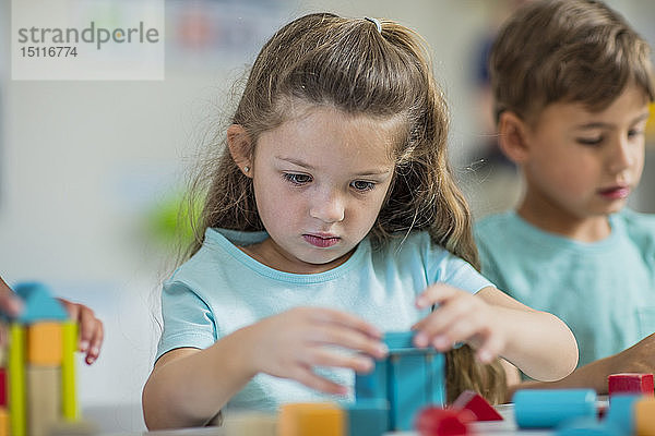 Fokussiertes Mädchen spielt im Kindergarten mit Bausteinen