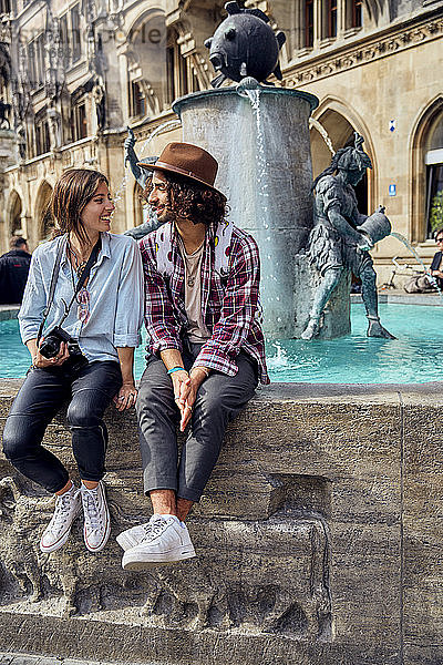 Junges Paar sitzt am Brunnen