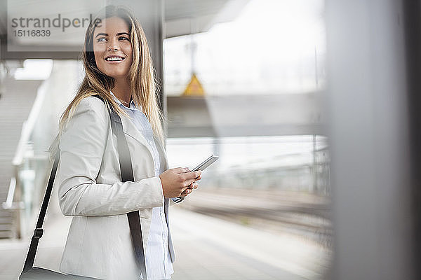 Junge Geschäftsfrau mit Tablette am Bahnhof stehend
