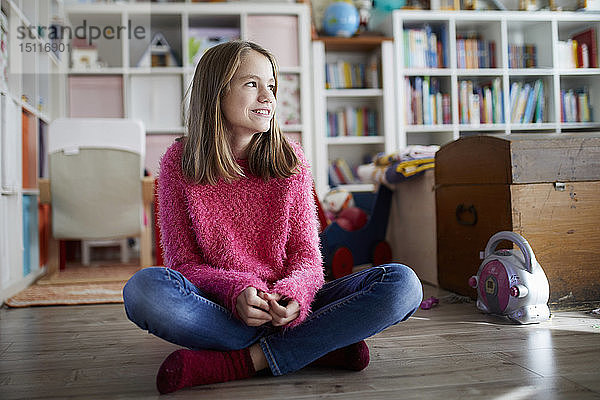 Selbstbewusstes Mädchen sitzt im Schneidersitz auf dem Boden ihres Zimmers