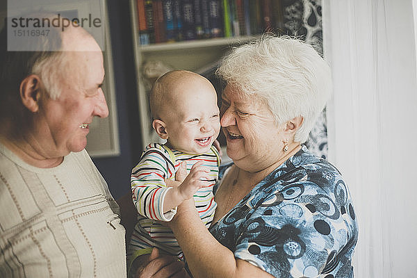 Glückliche Großeltern halten ihren kleinen Enkel
