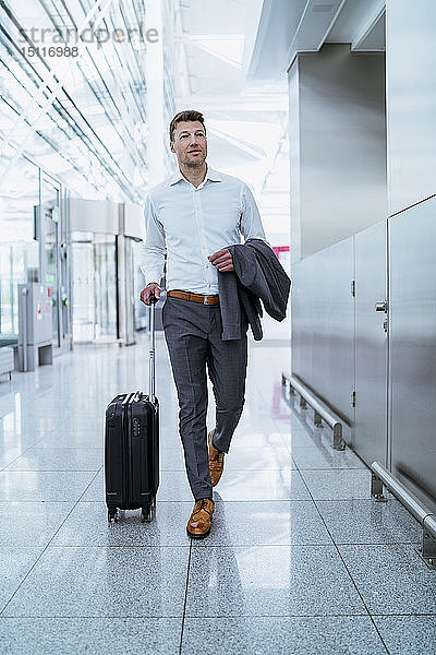 Geschäftsmann zu Fuß mit Gepäck am Flughafen