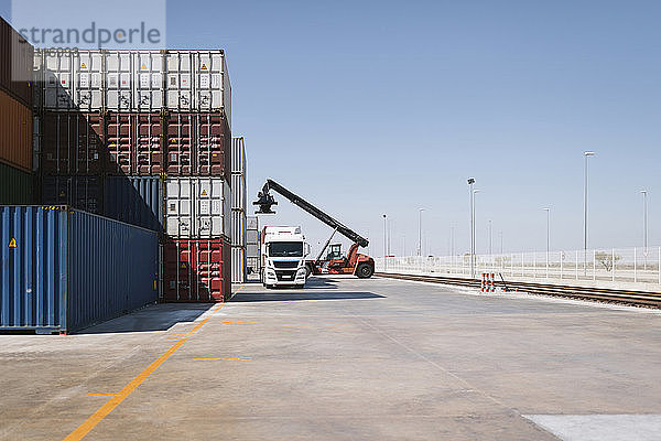 Kran hebt Frachtcontainer auf Lastwagen auf Industriegelände