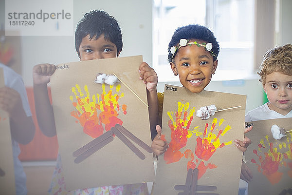 Porträt von lächelnden Kindern  die Bilder von Feuer im Kindergarten präsentieren