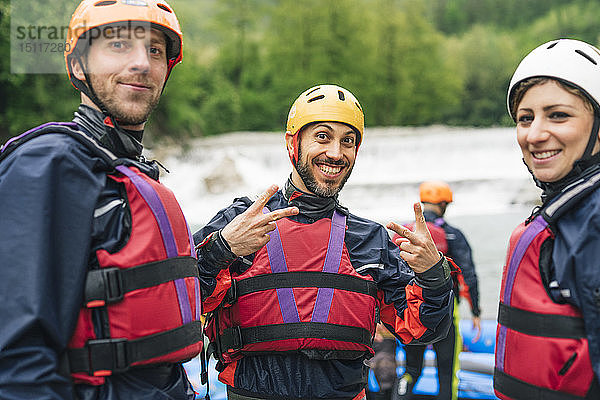 Glückliche Freunde bei einem Rafting-Kurs posieren am Flussufer