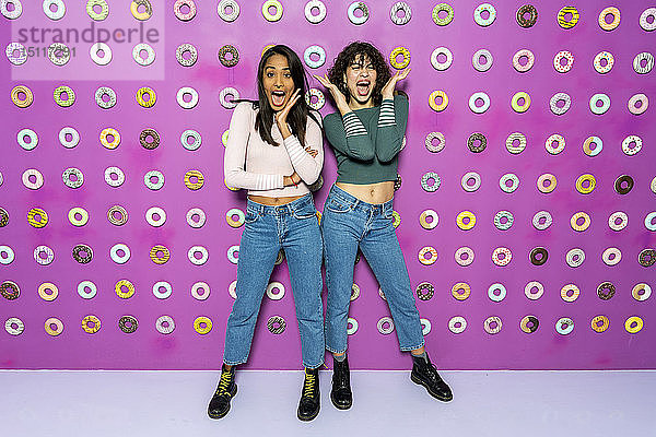 Zwei junge Frauen schreien einen Indoor-Themenpark mit Donuts an der Wand an