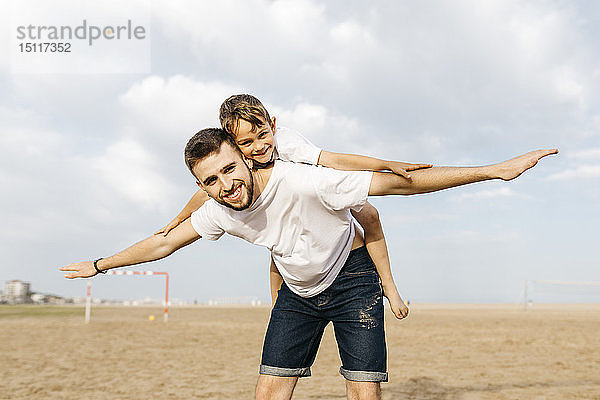 Mann trägt Junge huckepack am Strand