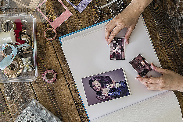 Draufsicht auf die Hände der Frau beim Gestalten des Fotoalbums