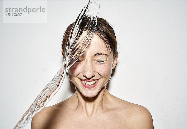 Porträt einer lachenden jungen Frau mit spritzendem Wasser