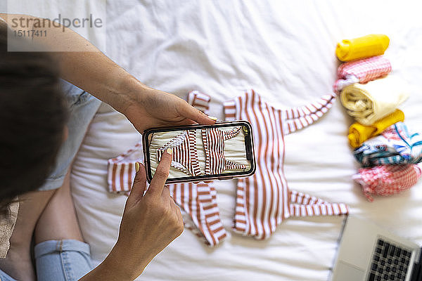 Frau macht Smartphone-Foto vom Bikini im Bett