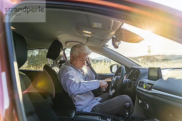 Älterer Mann in einem Auto beim Anlegen des Sicherheitsgurtes