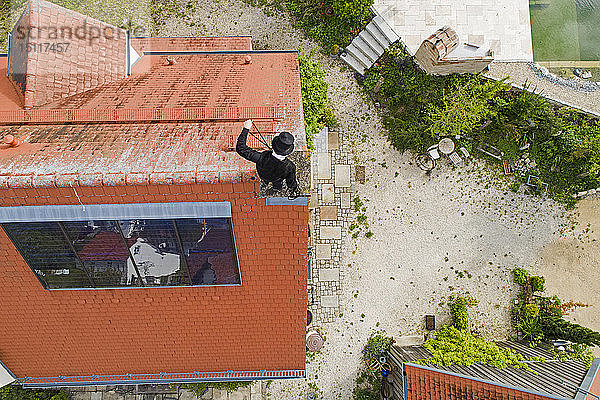 Luftaufnahme des Schornsteinfegers bei der Arbeit auf dem Hausdach