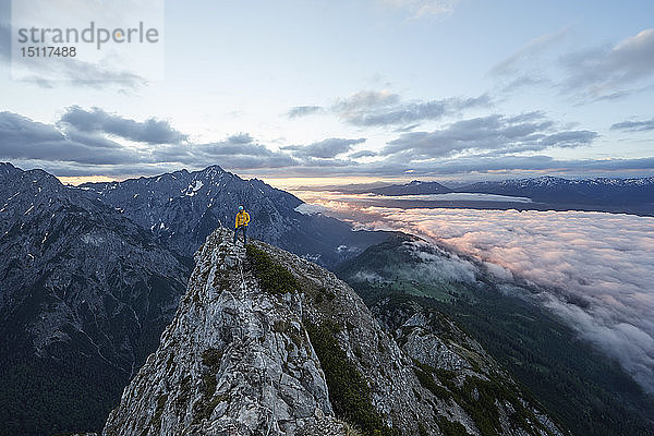 Österreich  Tirol  Gnadenwald  Hundskopf  männlicher Bergsteiger im Fels stehend im Morgenlicht