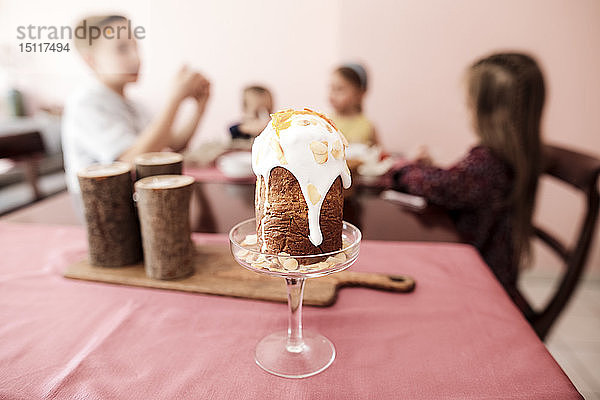 Garnierter Kuchen auf dem Tisch zu Hause mit Kindern im Hintergrund