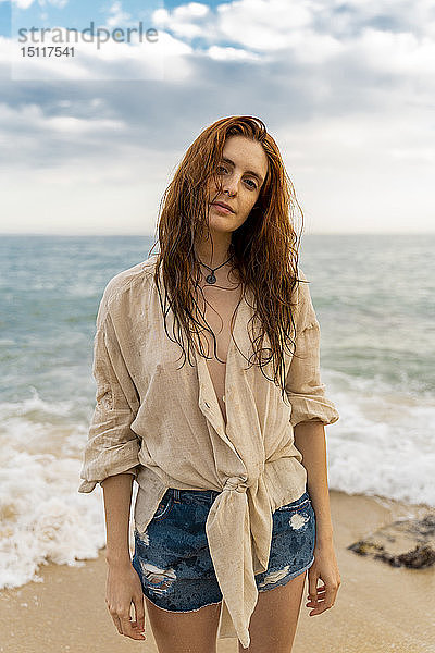 Porträt einer rothaarigen jungen Frau mit Nasenpiercing am Strand stehend