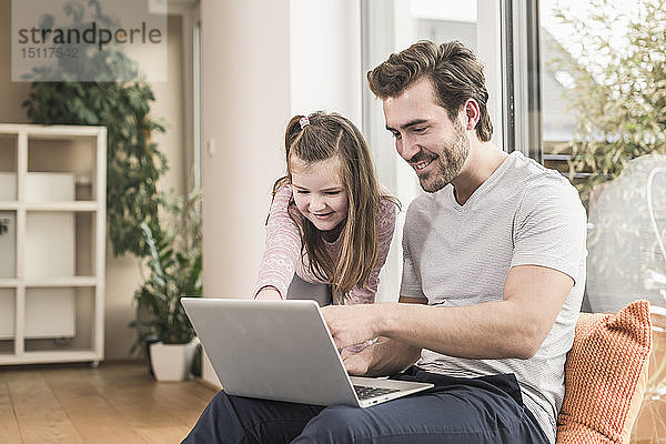Junger Mann und kleines Mädchen surfen gemeinsam im Netz