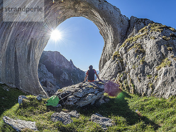 Spanien  Asturien  Pena Mea  Ojo de buey  Wanderer auf Fels sitzend