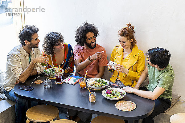 Gruppe glücklicher Freunde mit einer Sofortbildkamera beim Mittagessen in einem Restaurant