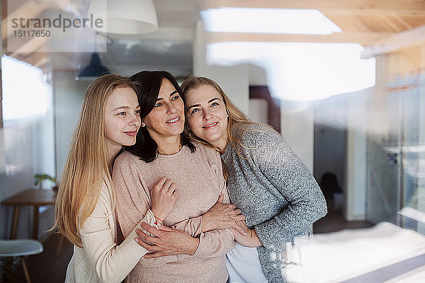 Besuchende Töchter  die ihre Mutter umarmen und am Fenster stehen