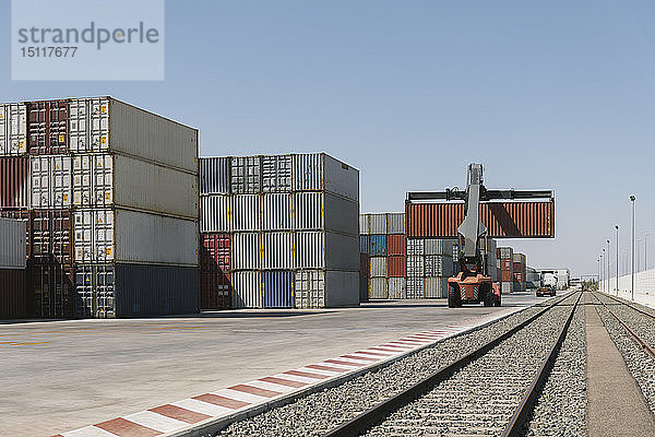 Kran zum Heben von Frachtcontainern in der Nähe von Eisenbahnschienen auf einem Industriegelände