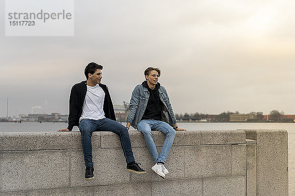 Dänemark  Kopenhagen  zwei junge Männer sitzen auf einer Mauer am Wasser