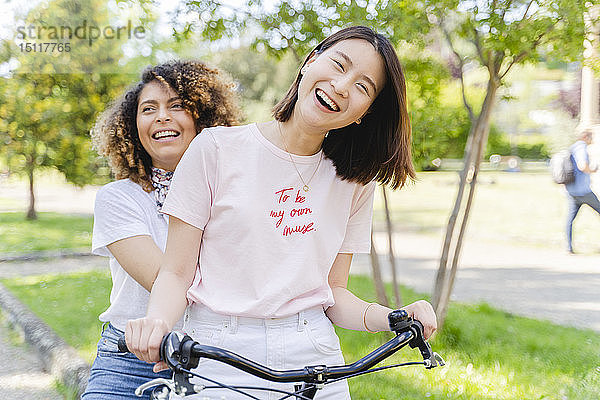 Zwei glückliche Frauen auf dem Fahrrad im Park