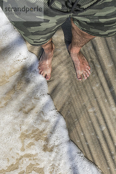 Die Füße eines Mannes  der an einem Sandstrand steht und die Wellen genießt  Cahuita-Nationalpark  Costa Rica
