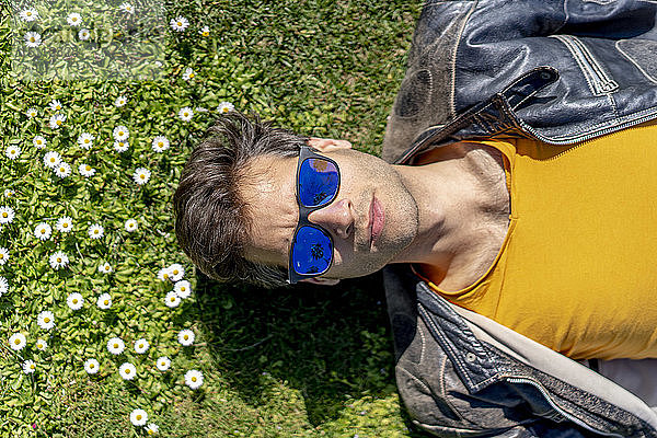 Auf Blumenwiese liegender Mann mit Sonnenbrille