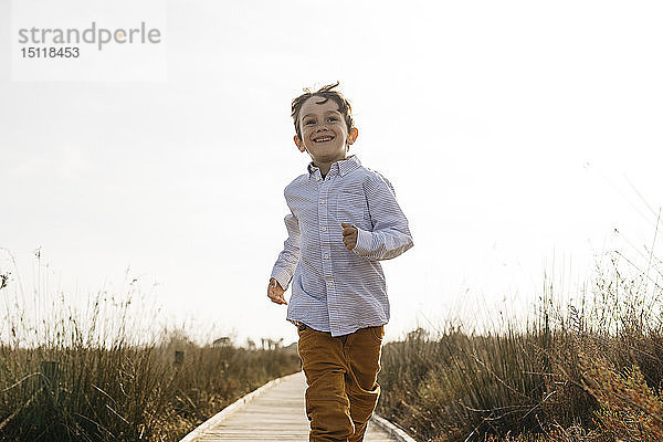 Porträt eines glücklichen kleinen Jungen beim Laufen auf der Promenade