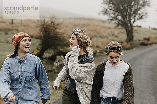 Großbritannien  Schottland  Isle of Skye  drei glückliche junge Frauen auf einer Landstraße