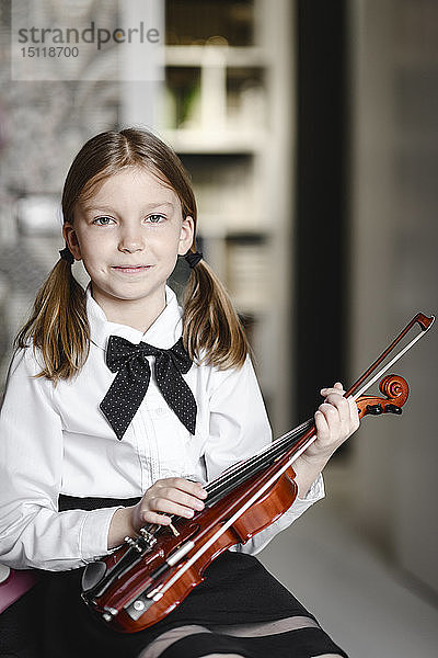 Porträt eines lächelnden Mädchens mit einer Geige zu Hause