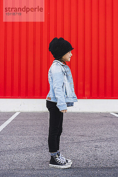 Modisches kleines Mädchen in Jeansjacke  schwarzer Mütze und Turnschuhen