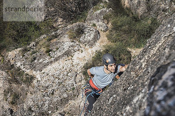 Mann klettert in Felswand