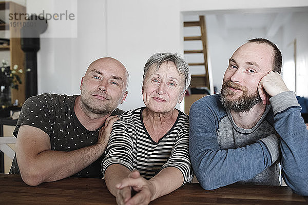 Porträt von lächelnden erwachsenen Söhnen mit älterer Mutter zu Hause