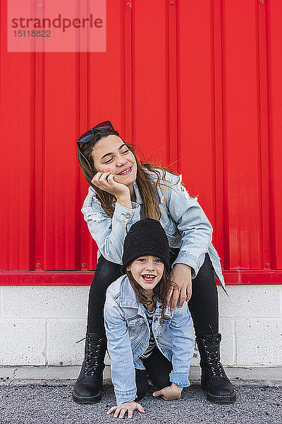 Porträt einer lächelnden Teenagerin mit ihrer jüngeren Schwester im Freien
