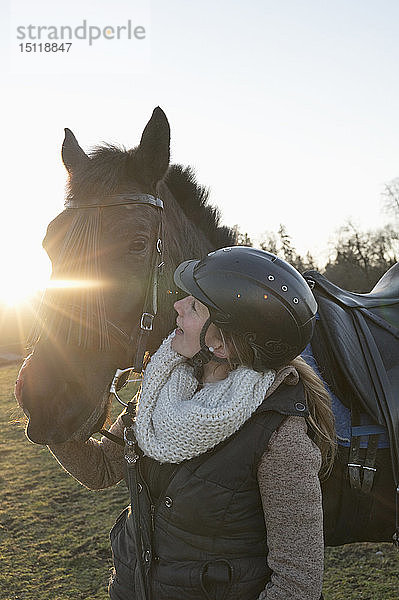 Junge Frau mit Pferd im Gegenlicht