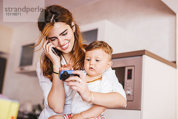 Glückliche Mutter mit ihrem Sohn telefoniert zu Hause