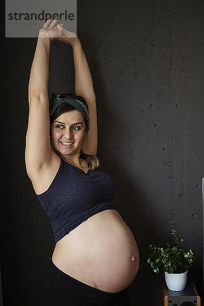 Schwangere Frau zeigt ihre Babyglocke  streckt die Arme