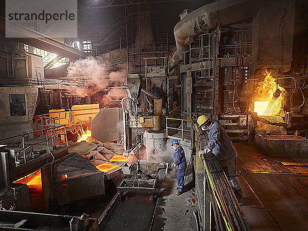 Industrie  Arbeiter hebt Kupferplatten mit Hallenkran zur Kühlung im Wasserbecken