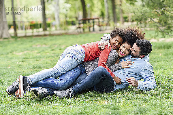 Glückliche Familie  die sich umarmt  auf Gras in einem Park liegt