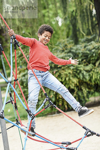 Kleiner Junge spielt auf einem Spielplatz in einem Park  klettert in einer Kletterhalle im Dschungel