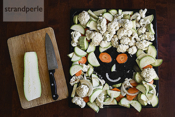 Lustiges Gesicht aus geschnittenem Gemüse auf Backblech