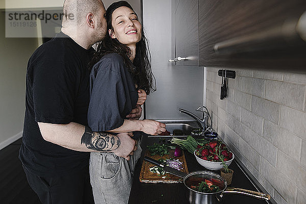 Mann umarmt und küsst Frau in der Küche
