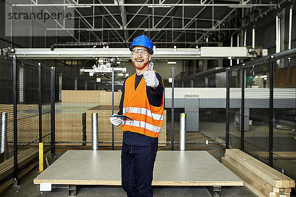 Porträt eines glücklichen Arbeiters mit Tablette im Fabriklager
