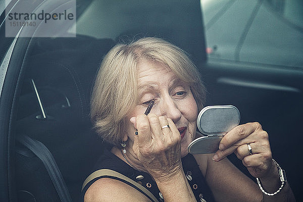 Ältere Frau beim Schminken im Auto