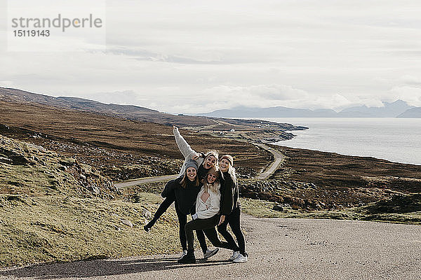 Großbritannien  Schottland  Highland  glückliche Freundinnen auf einer Straße an der Küste