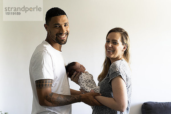 Porträt von glücklichen Eltern  die ihr Neugeborenes zu Hause halten